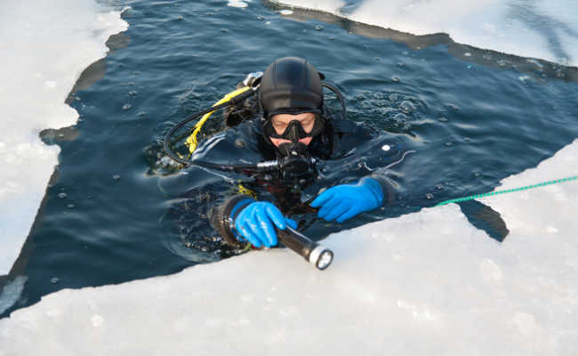 Plongeur sous la glace avec une combinaison de plongé et un masque à oxygène