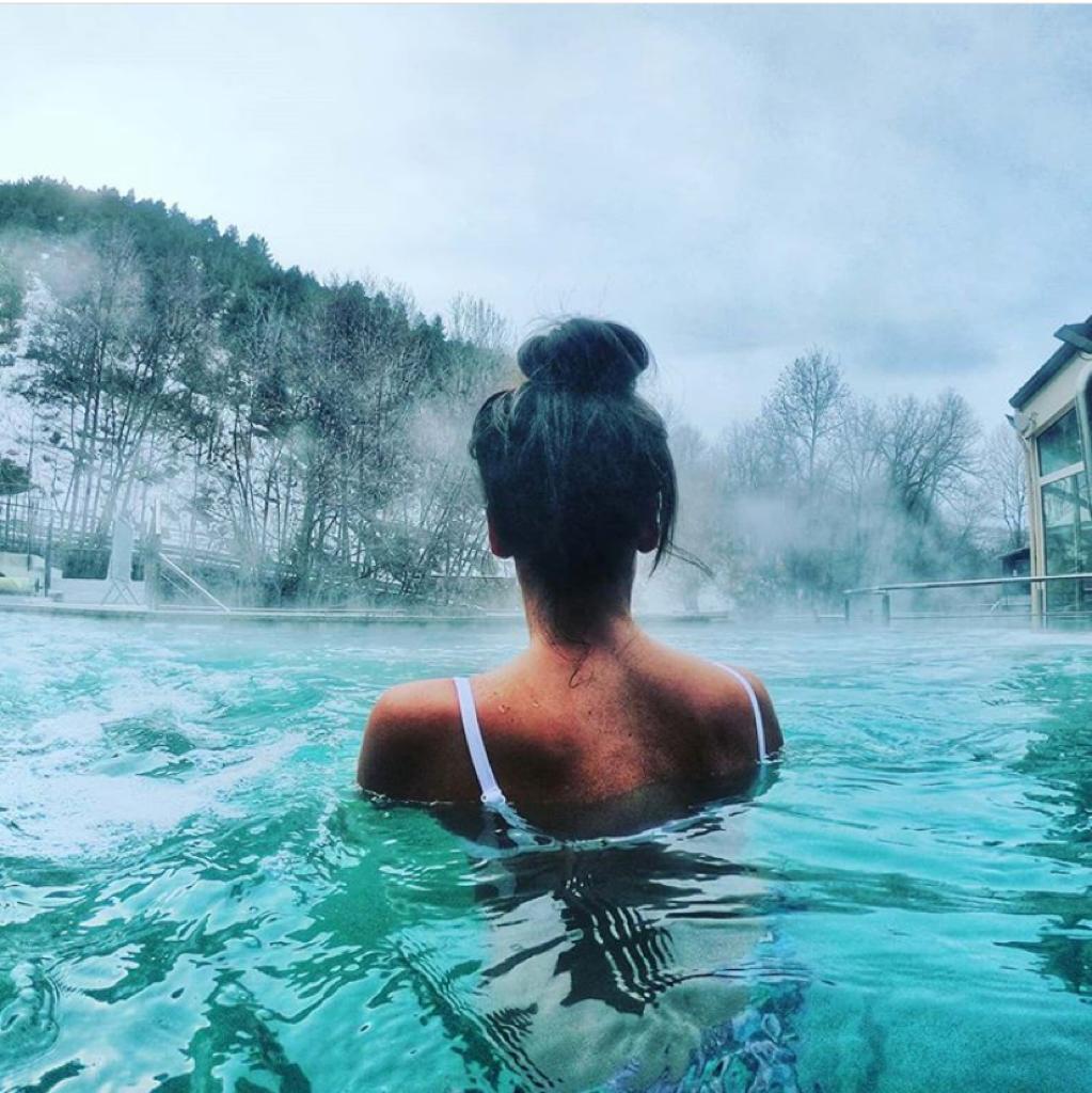 femme se baignant dans une piscine extérieur en hiver avec de la buée au dessus
