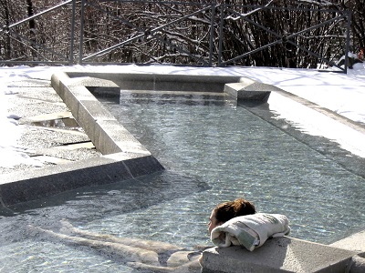 une femme se détend dans une piscine extérieur avec une serviette en guise de coussin