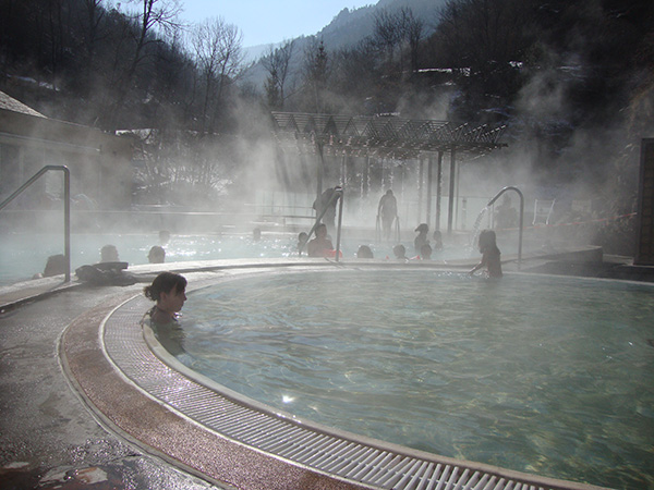 femme se baignant dans le jacuzzi extérieur en hiver avec de la buée au dessus