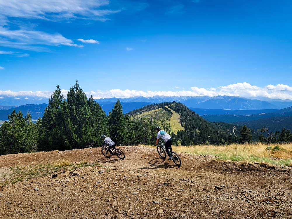 Formiguères-piste-avce-vue Deux vététistes roulent sur une piste de VTT au sommet de la station de Formiguères.
